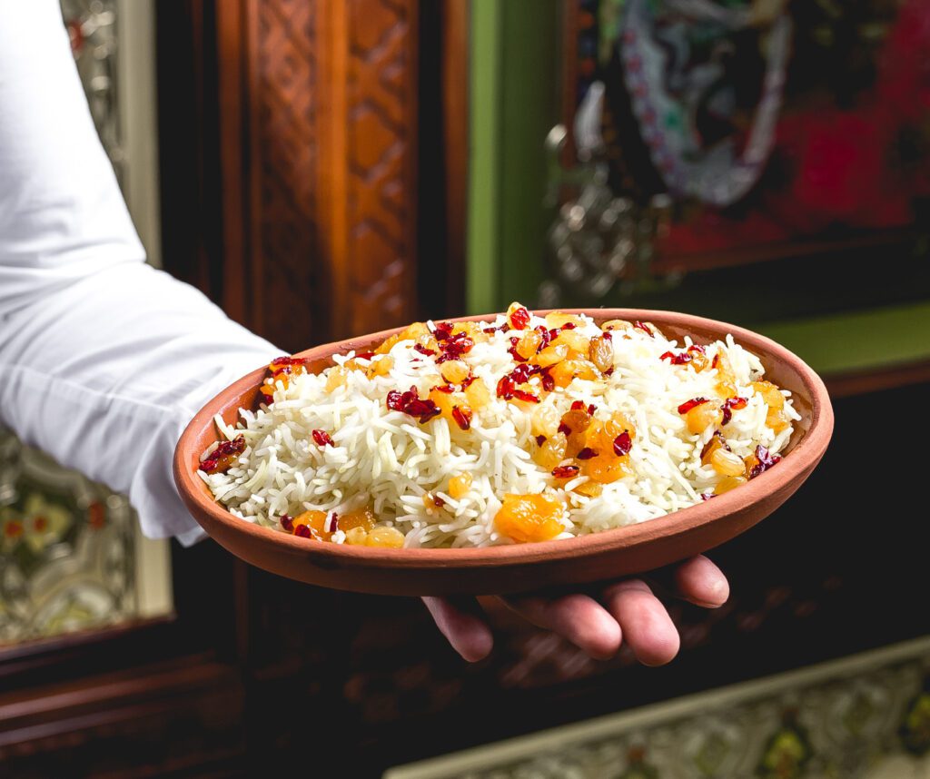 side view man holds plate with boiled rice with raisins barberries